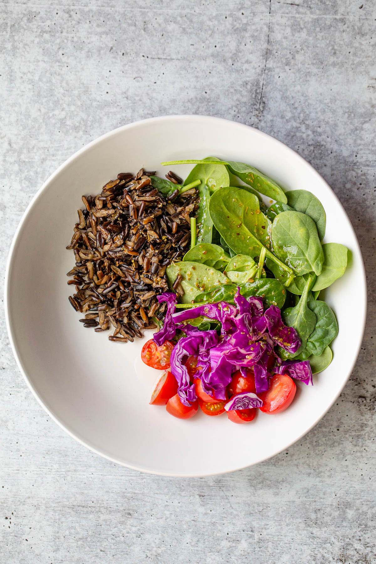 Grains and greens and veggies in a white bowl