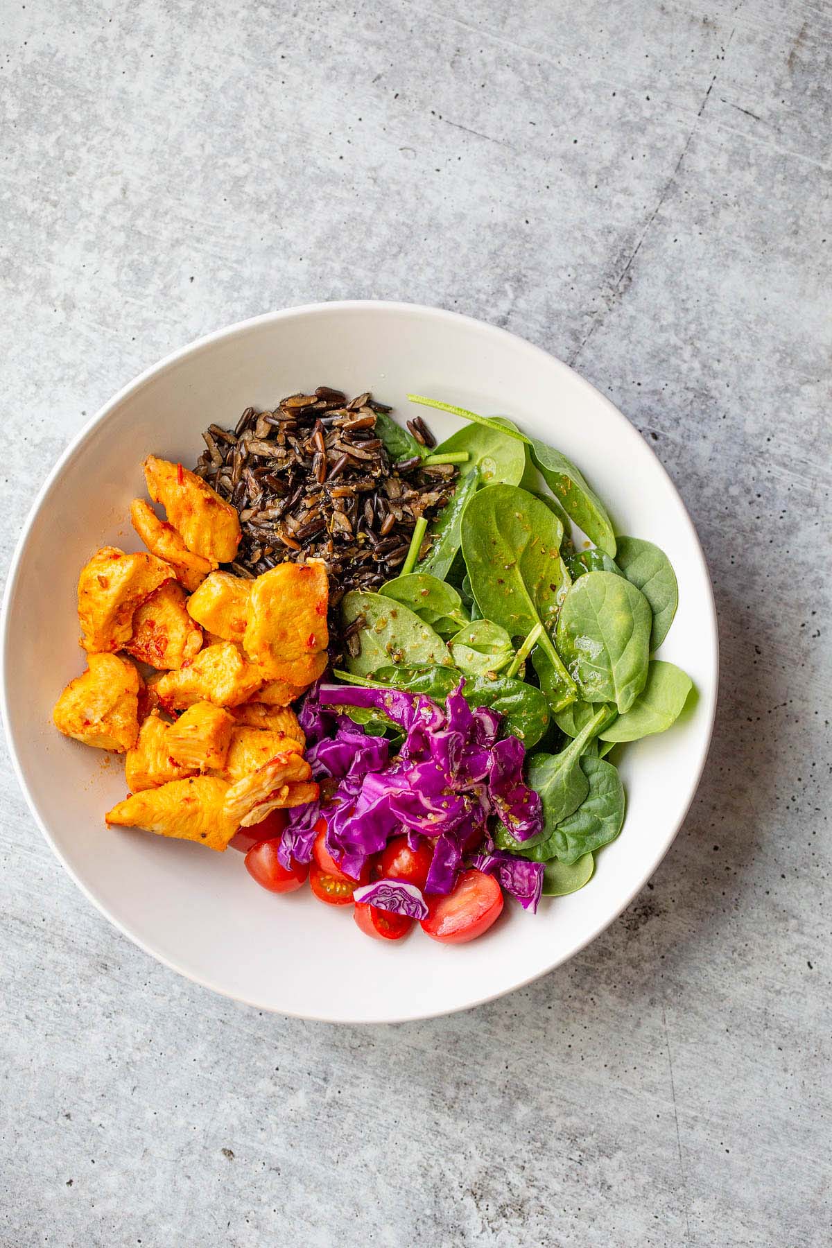 Grains and greens and veggies in a white bowl