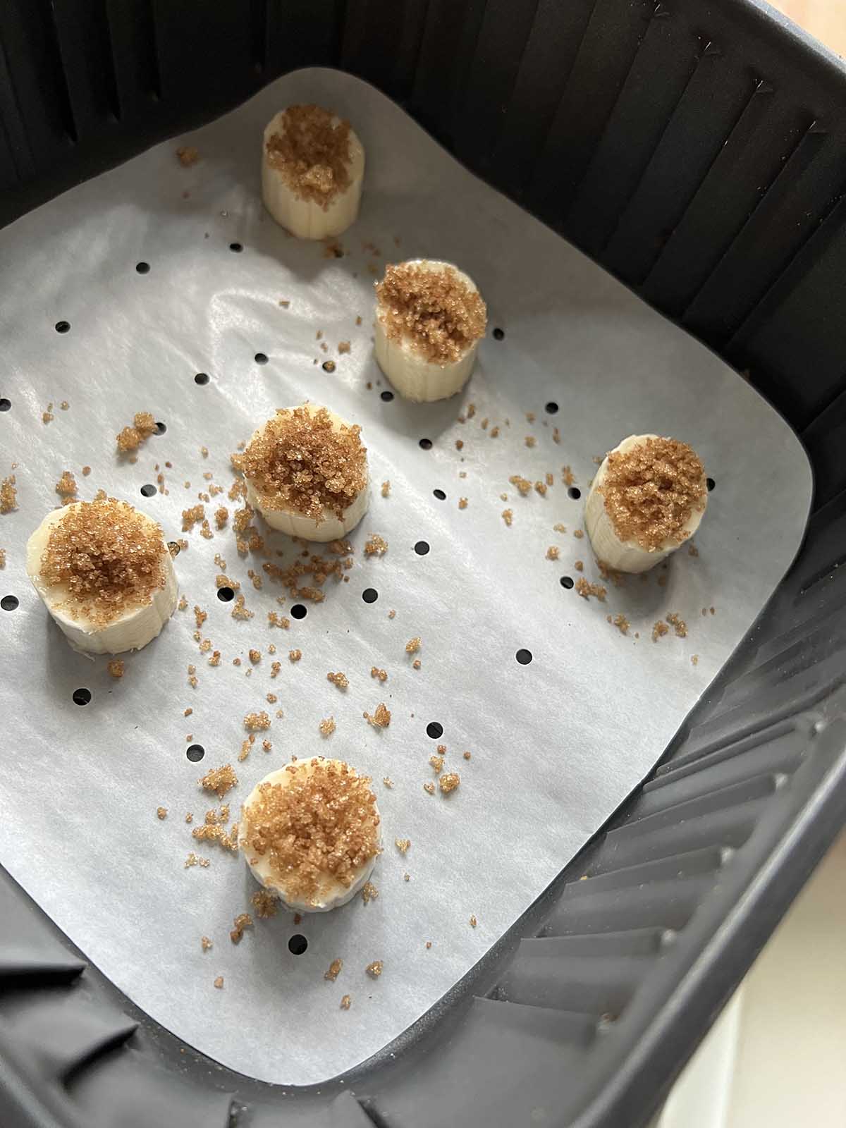 Banana slices with brown sugar on top in the air fryer basket