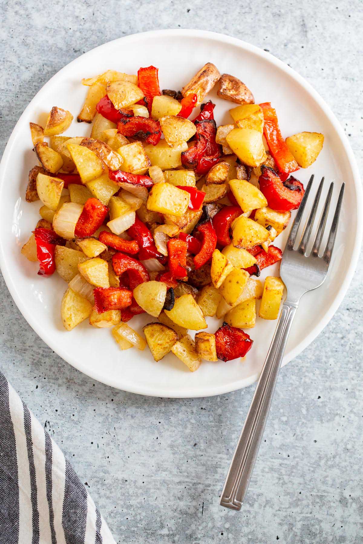 Air Fryer breakfast potatoes on a white plate with a fork.