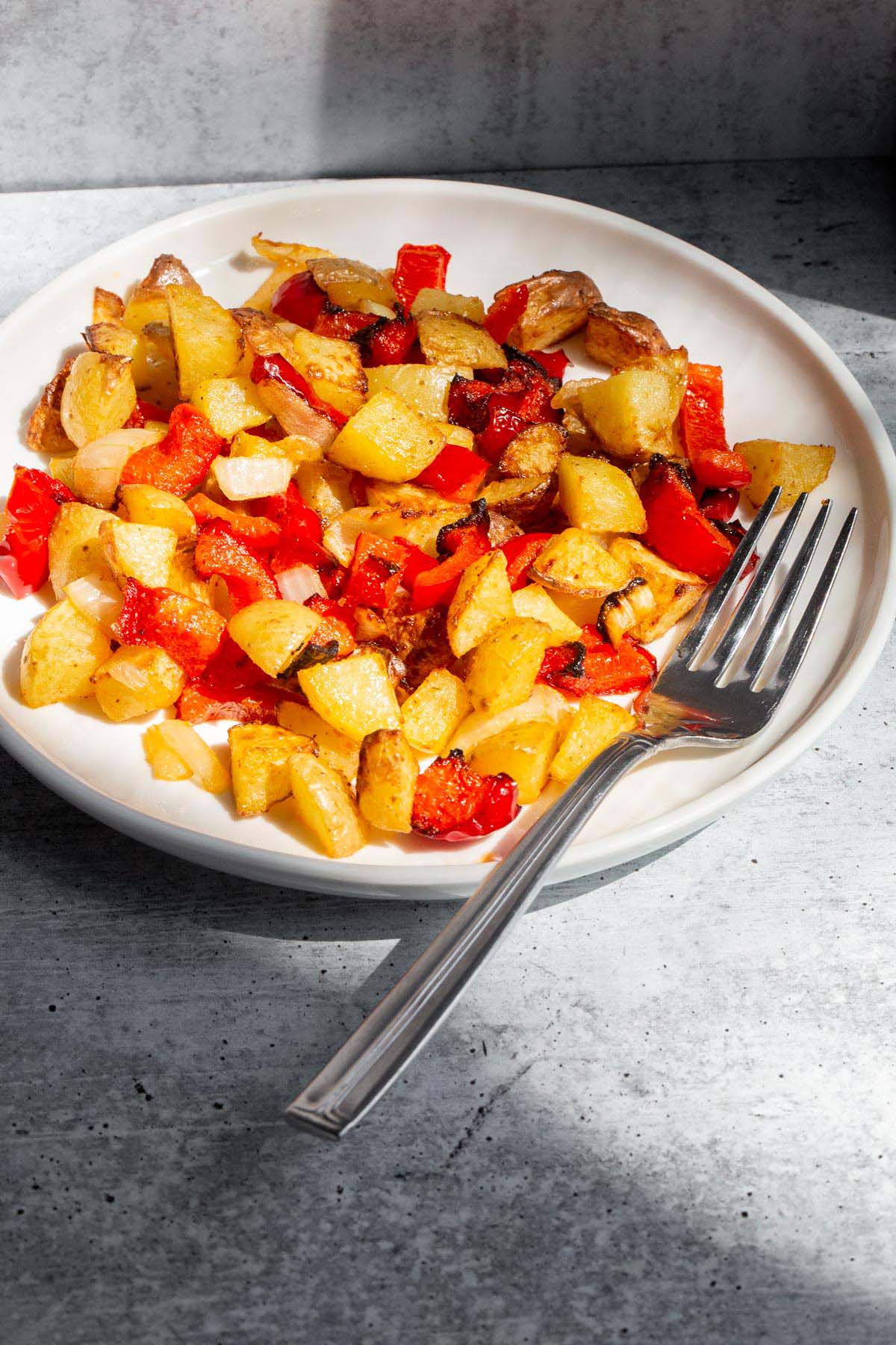 Air Fryer breakfast potatoes on a white plate with a fork.