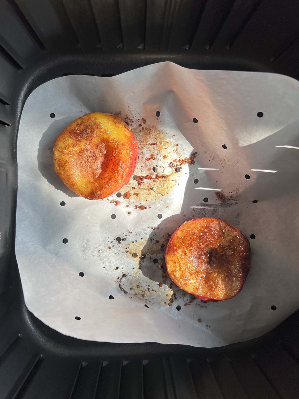 Cooked peaches in air fryer basket.