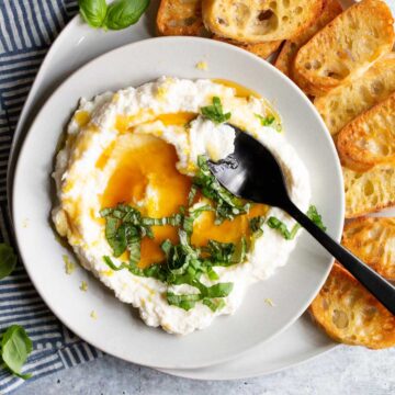 ricotta in a bowl topped with honey and lemon zest with a black spoon