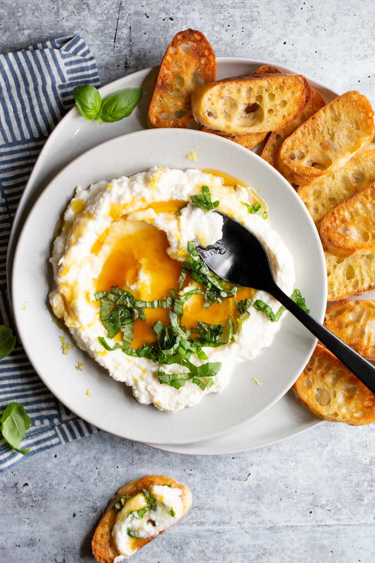 ricotta in a bowl topped with honey and lemon zest with a black spoon