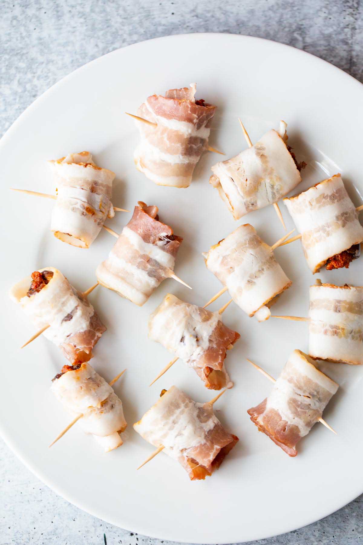 Uncooked bacon wrapped dates on a plate.