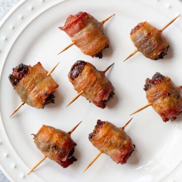 Cooked bacon wrapped dates on a plate.