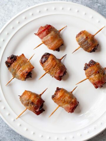 Cooked bacon wrapped dates on a plate.