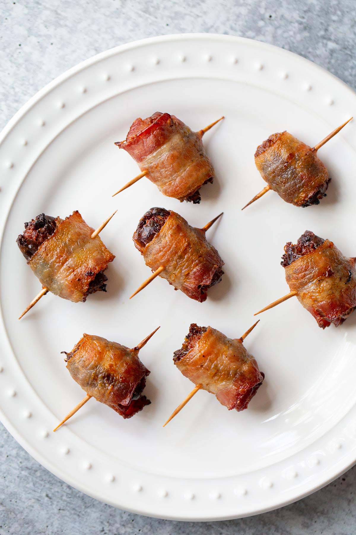 Cooked bacon wrapped dates on a plate.