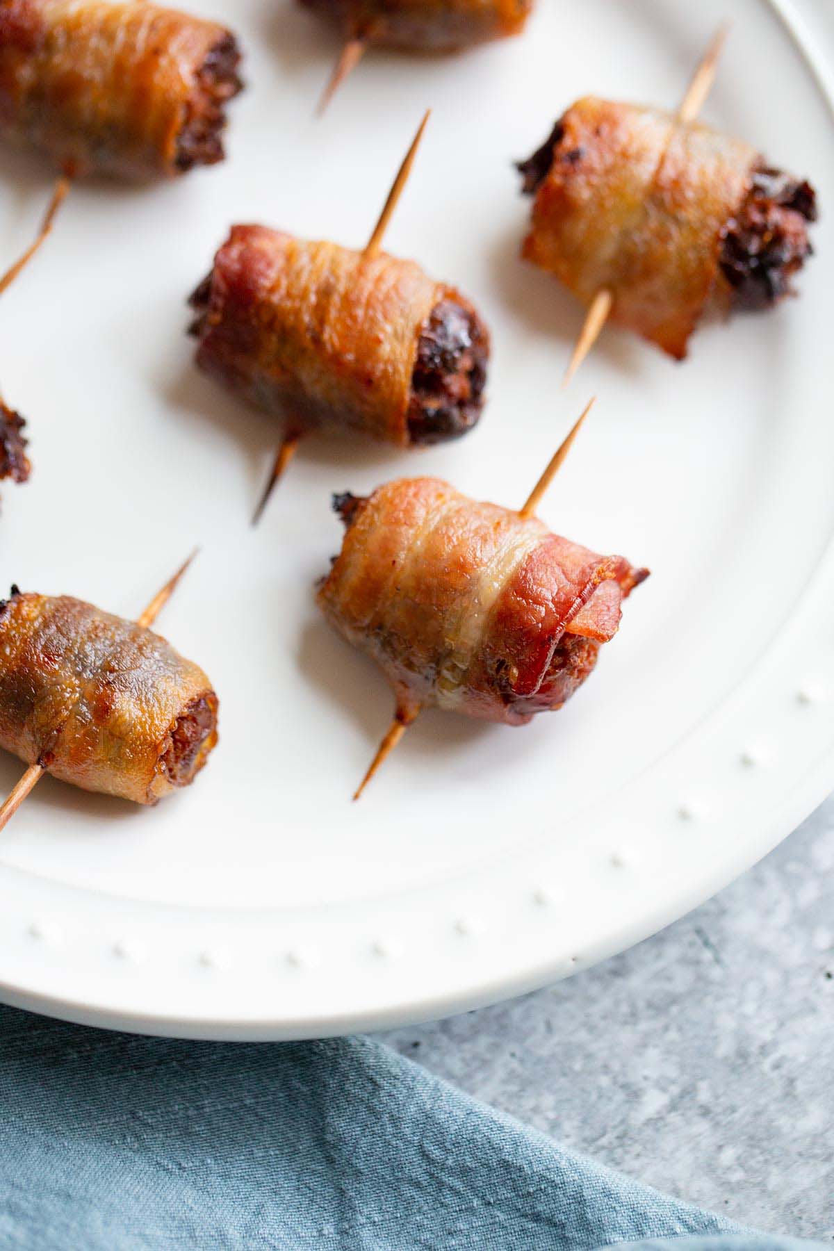 Cooked bacon wrapped dates on a plate.