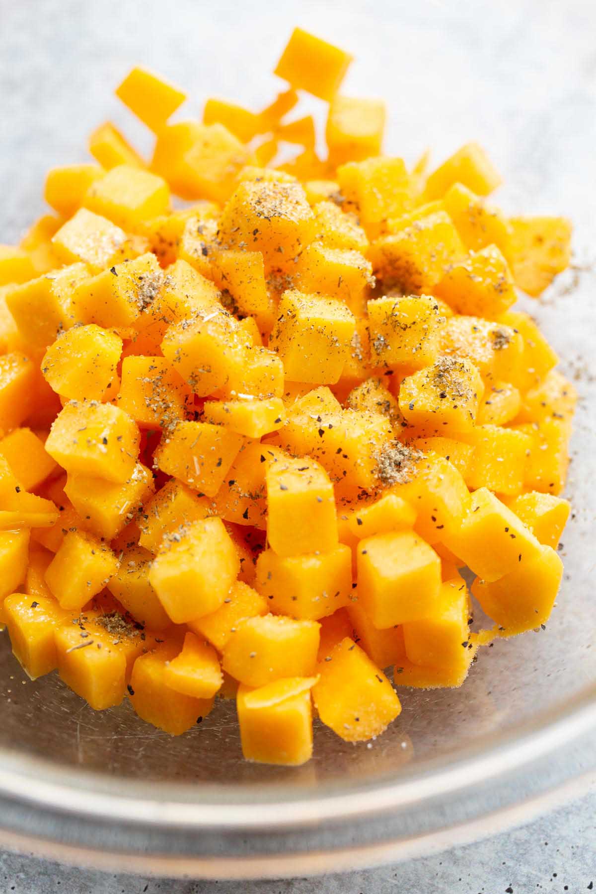 Butternut squash cubes in a bowl with seasoning