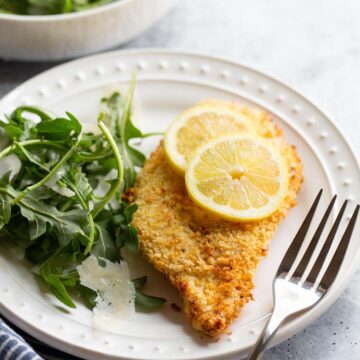 Air fried chicken cutlet with lemon slices and an arugula salad