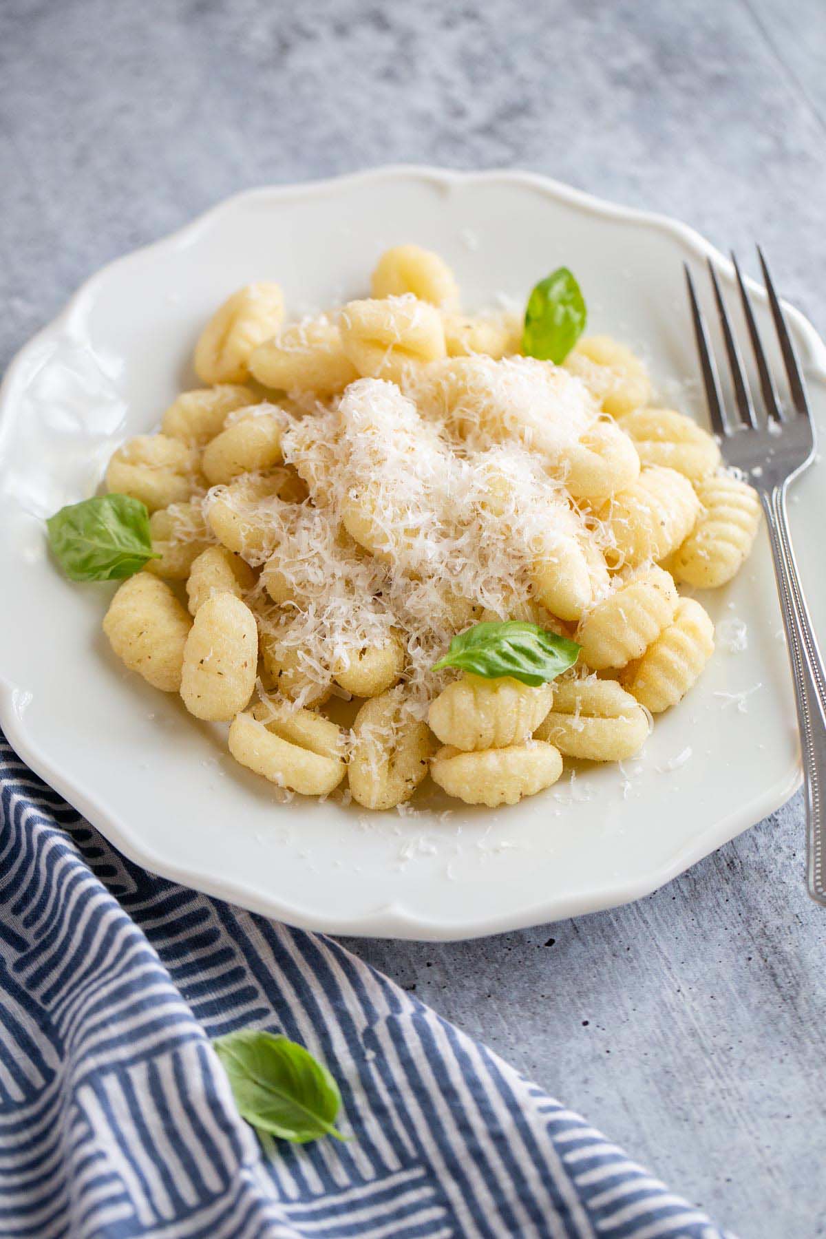 gnocchi on a plate with parmesan cheese and basil leaves.