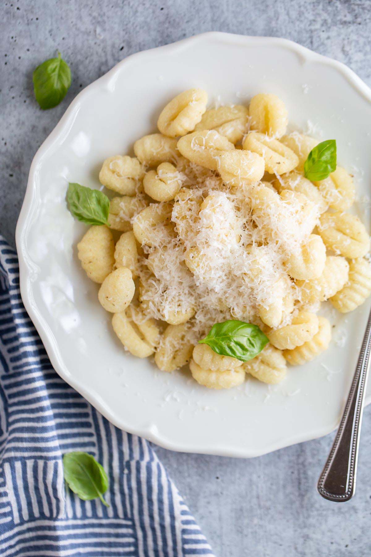 gnocchi on a plate with parmesan cheese and basil leaves.