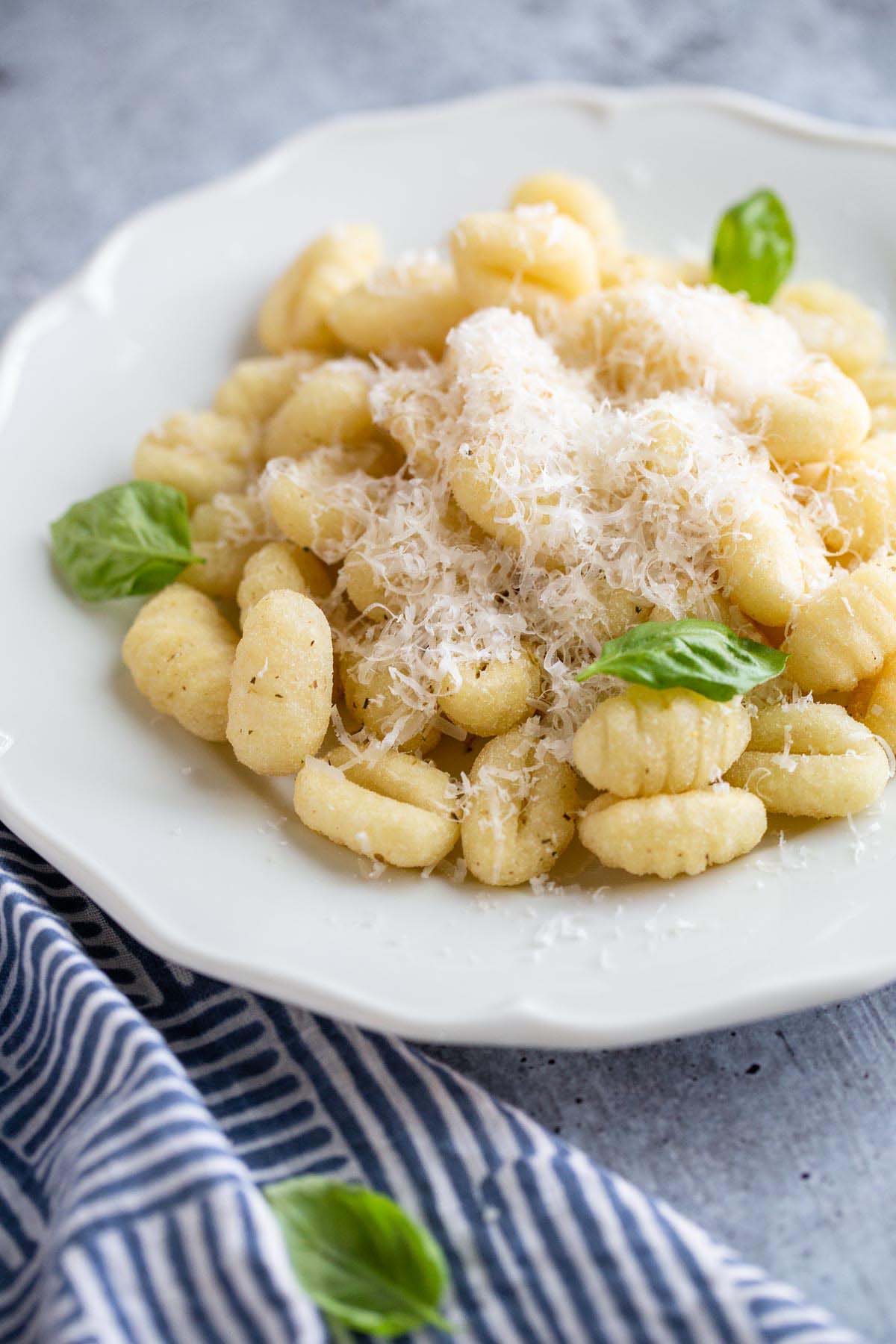 gnocchi on a plate with parmesan cheese and basil leaves.