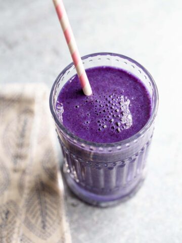 spirulina smoothie in a glass with a pink and white straw