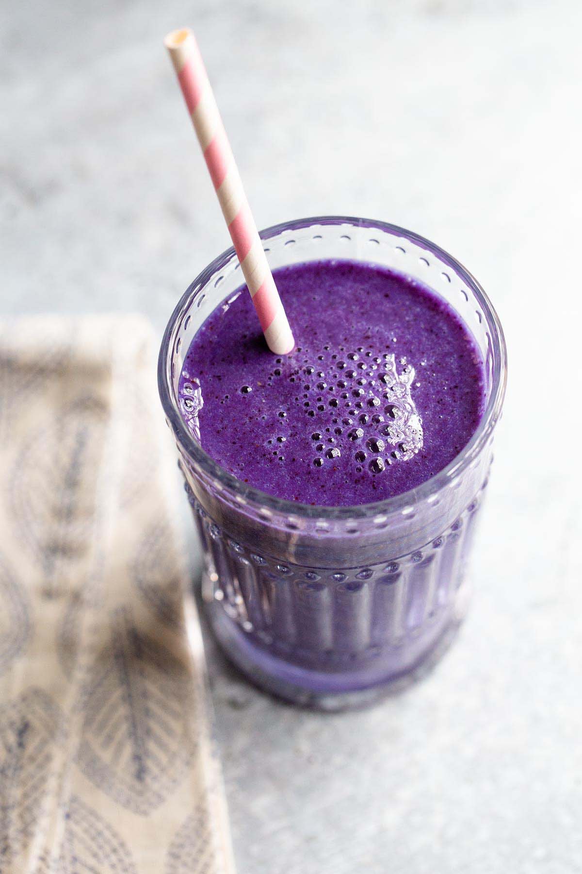 spirulina smoothie in a glass with a pink and white straw