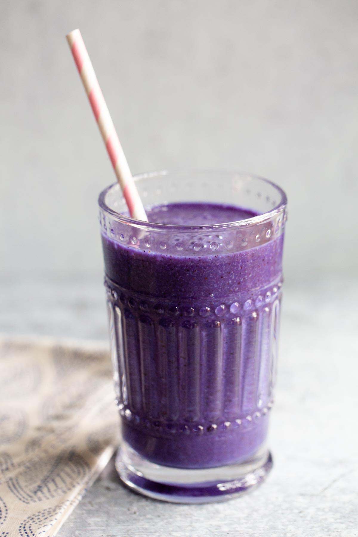 spirulina smoothie in a glass with a pink and white straw