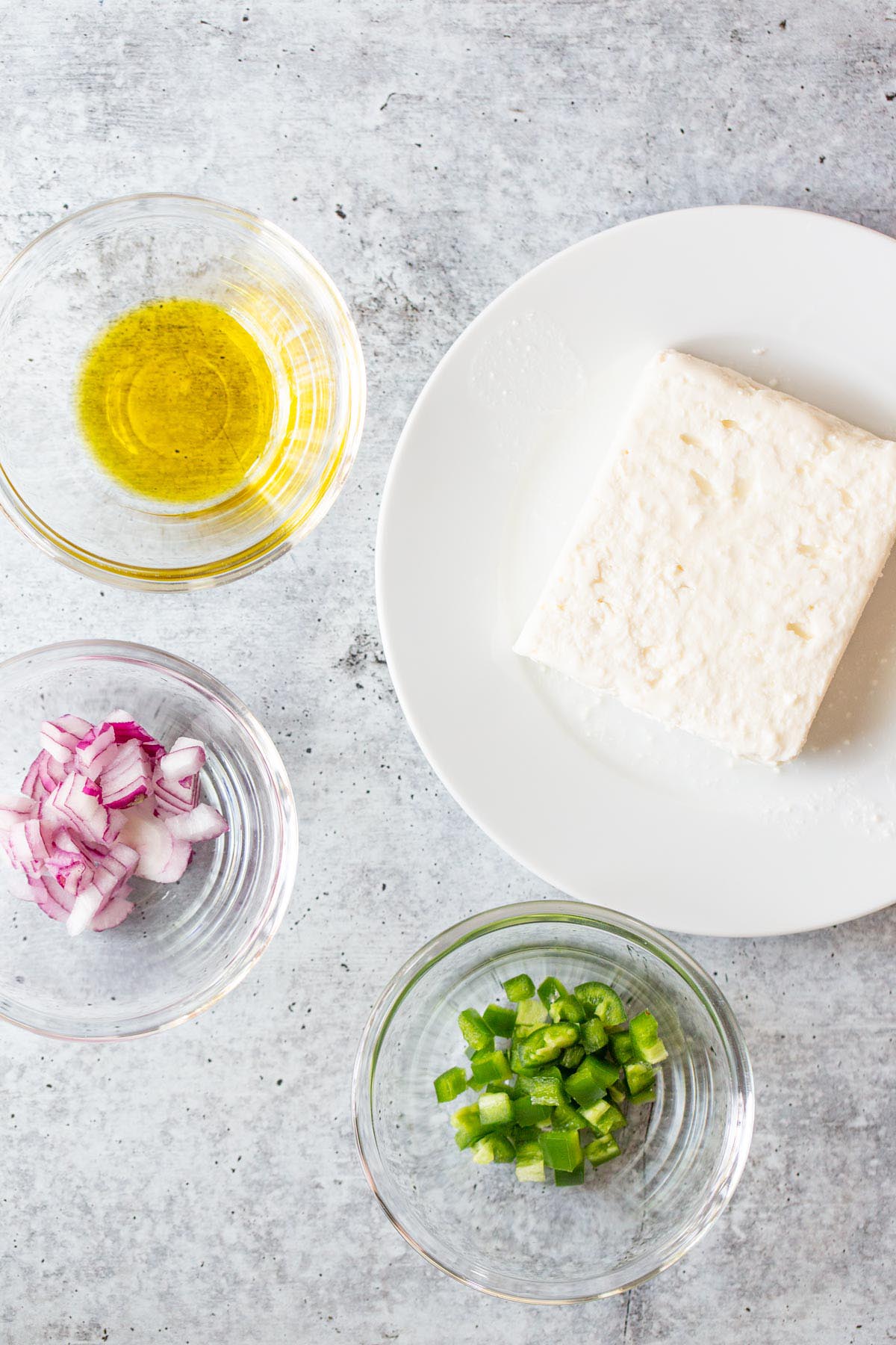 Ingredients for spicy feta dip - jalapenos, diced red onion, block of feta cheese, olive oil.