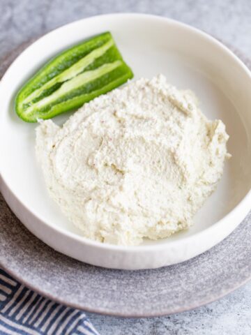 Spicy feta dip in a bowl with a jalapeno on the side.