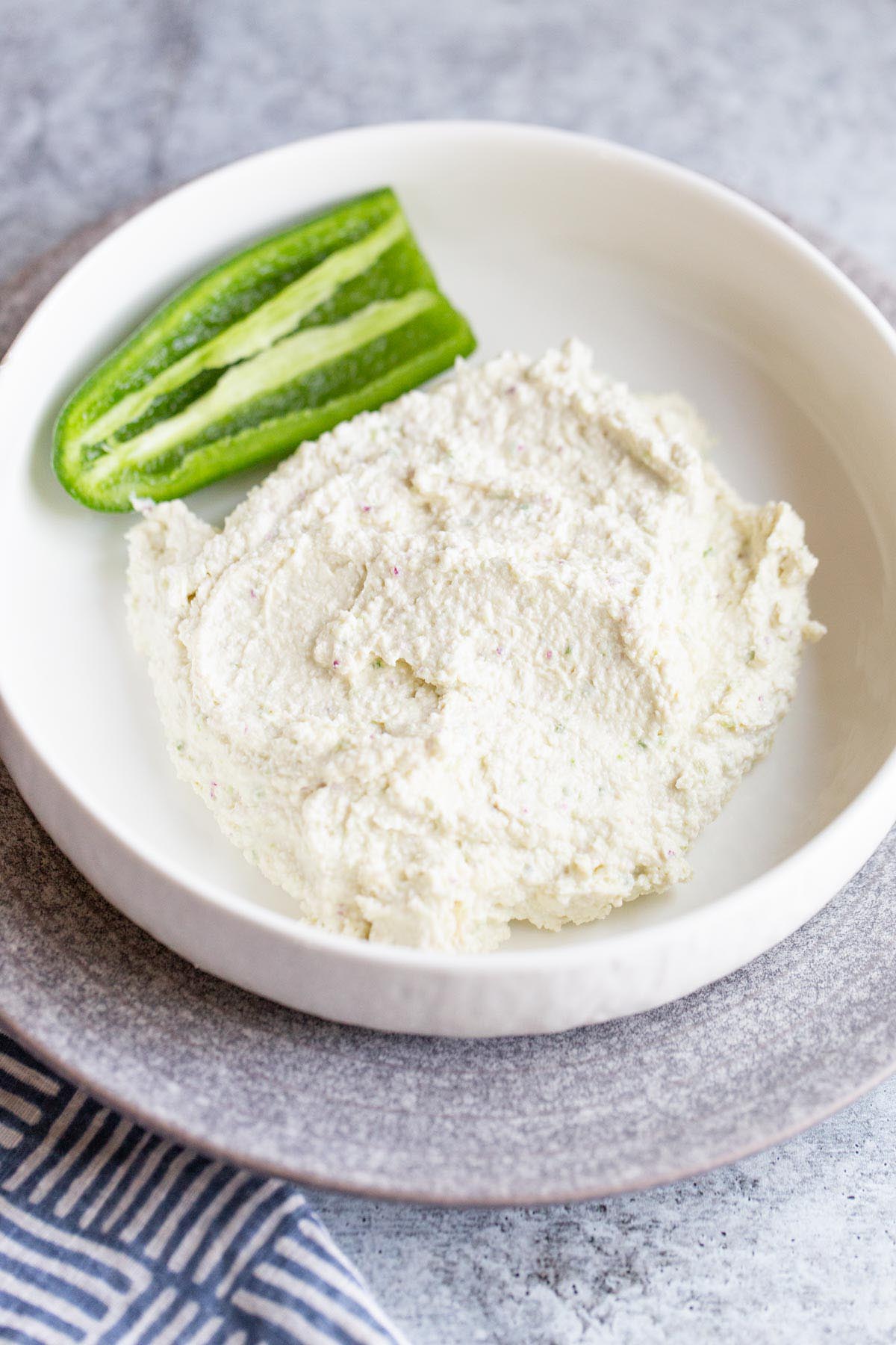 Spicy feta dip in a bowl with a jalapeno on the side.