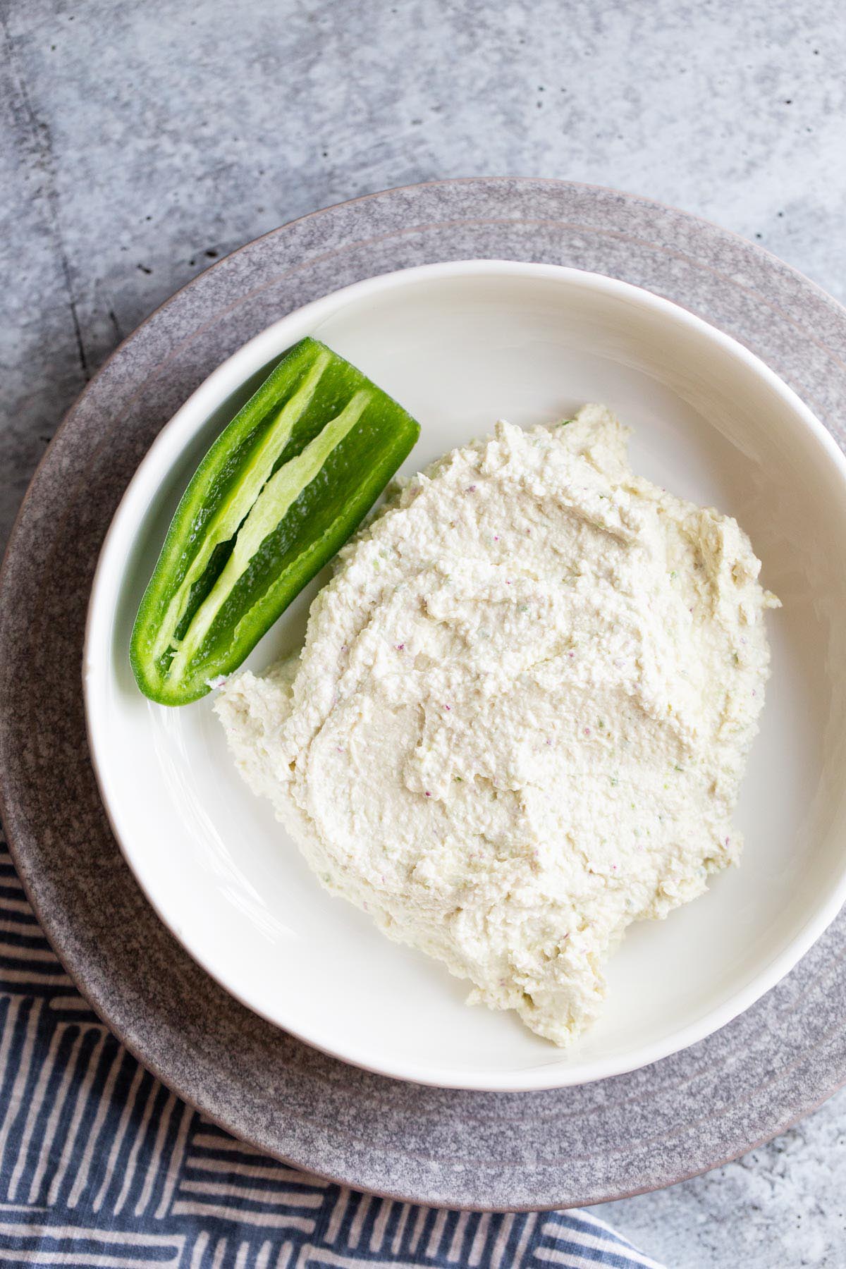 Spicy feta dip in a bowl with a jalapeno on the side.