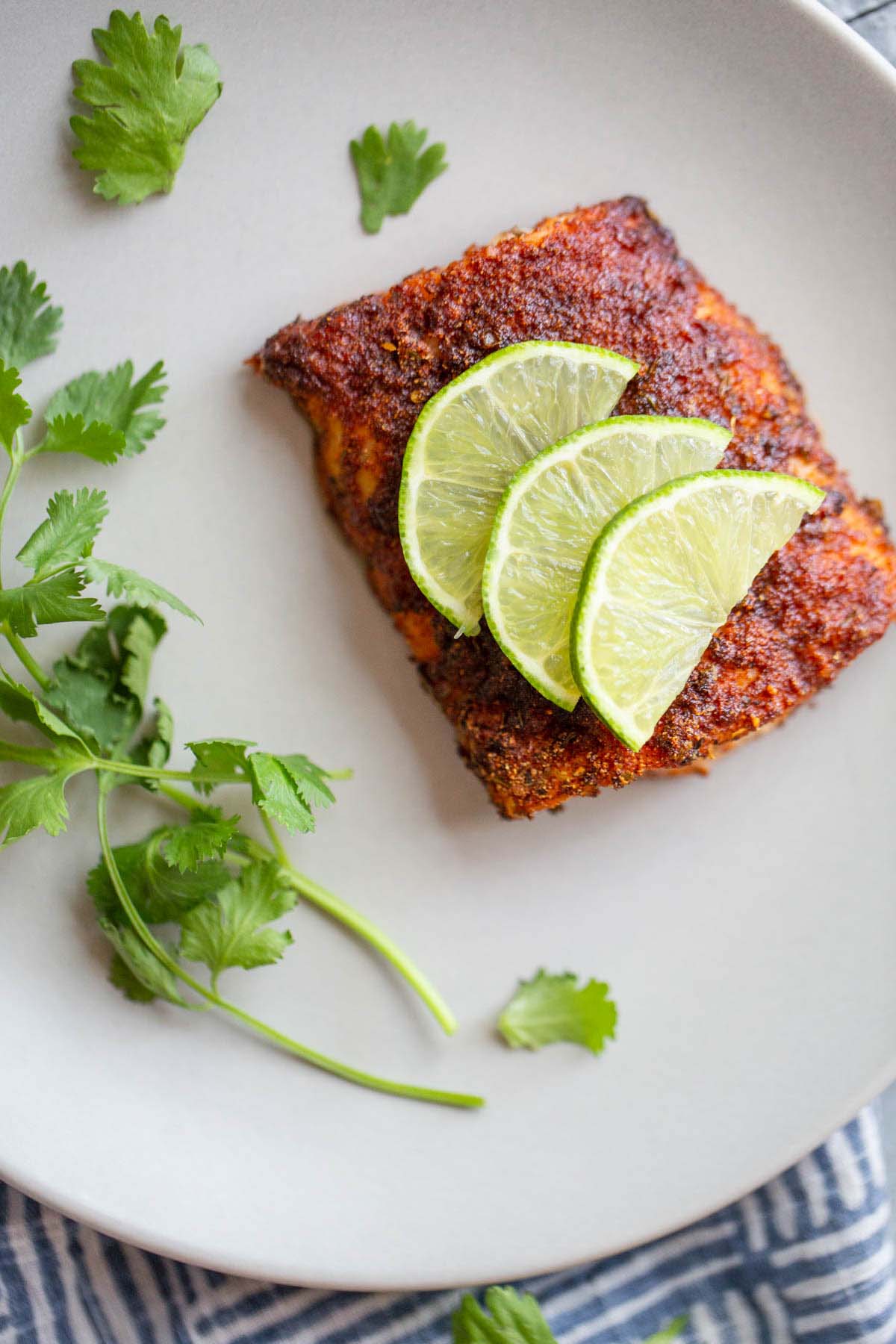 Blackened cod with lime slices on a white plate.