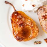 Air fried pears on a white plate with whipped cream and pecans.