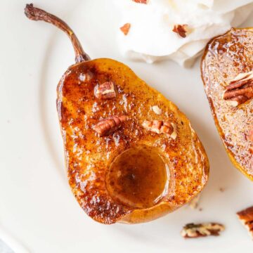Air fried pears on a white plate with whipped cream and pecans.