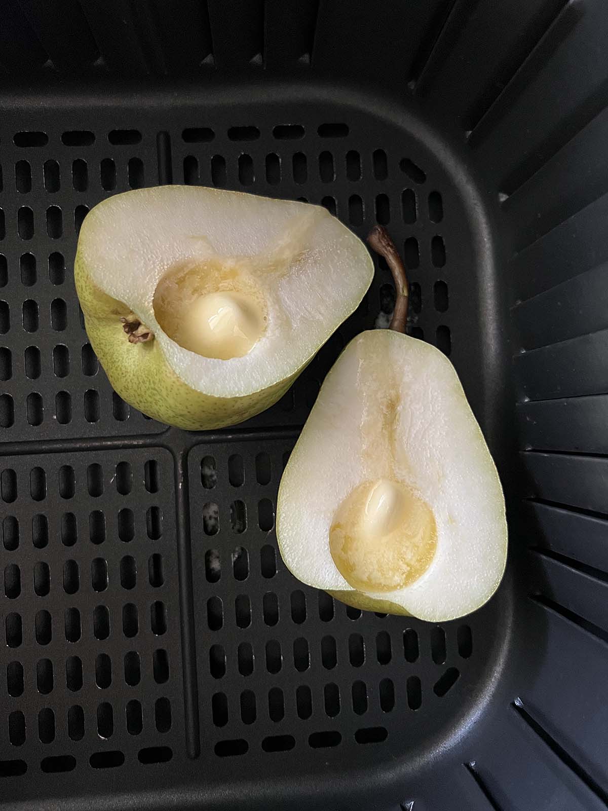 Pears in air fryer basket with melted butter.