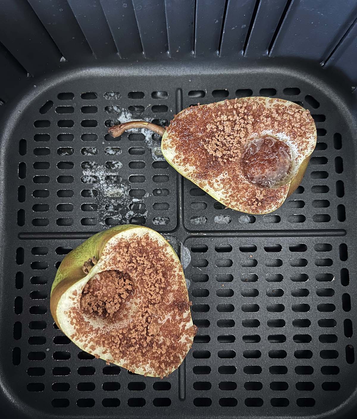 Pears in air fryer basket sprinkled with cinnamon sugar.