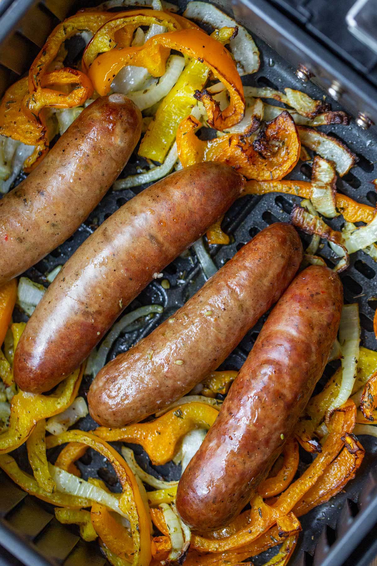 Cooked sausage and peppers in air fryer basket.