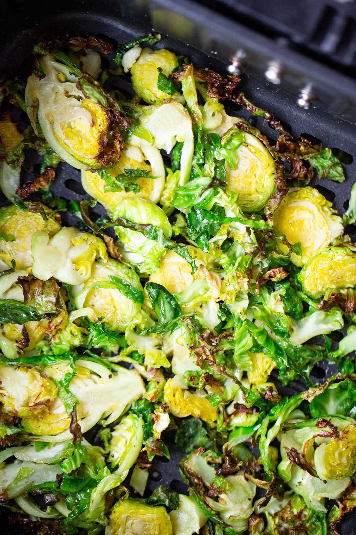 Cooked brussels sprouts in air fryer basket.