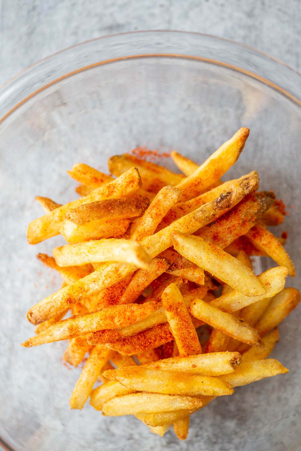 French fries with peri-peri seasoning in a glass bowl.