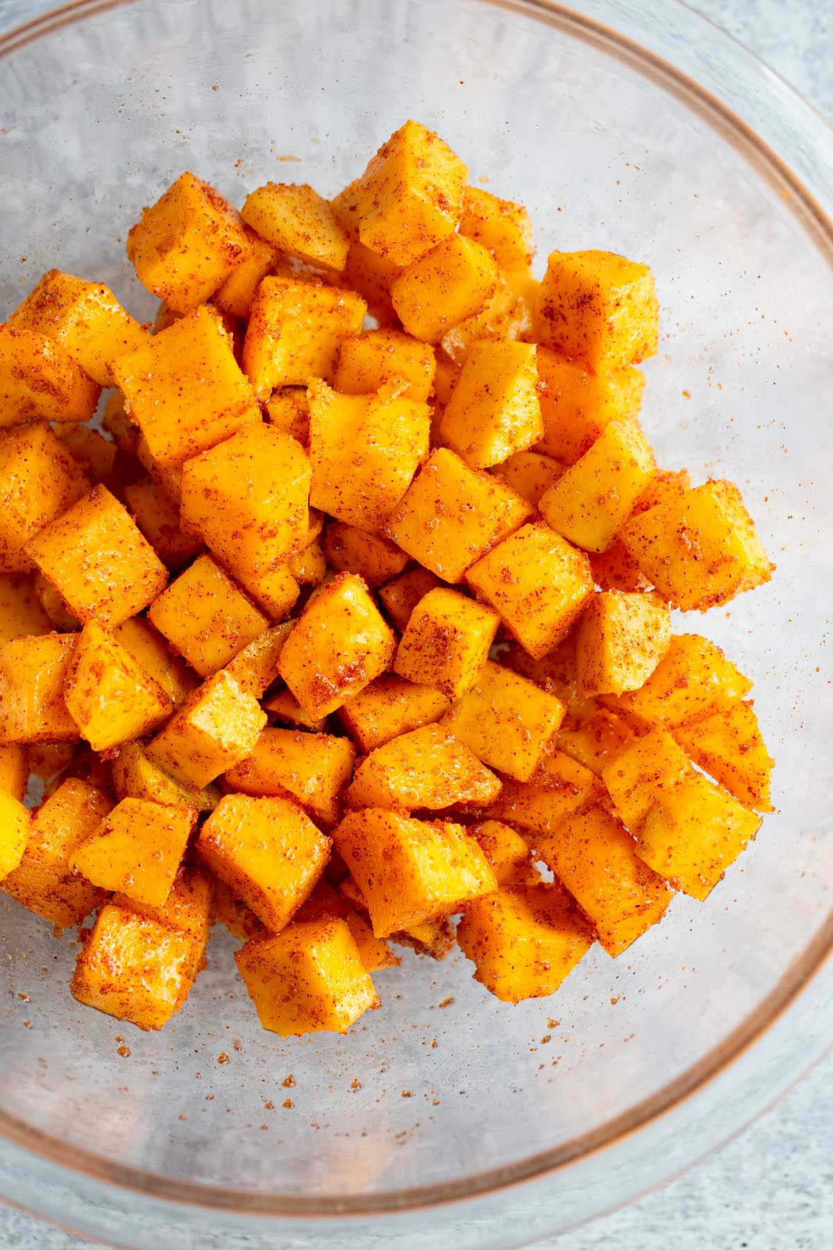 Butternut squash in a bowl tossed with spices and brown sugar.