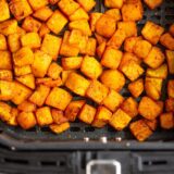 Cooked butternut squash cubes in the air fryer basket.
