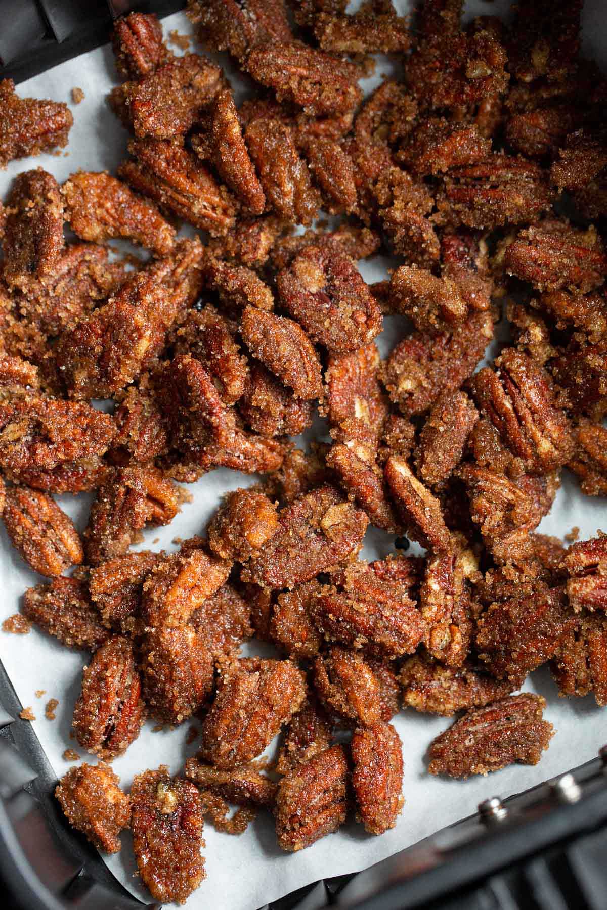 Uncooked candied pecans in air fryer basket.