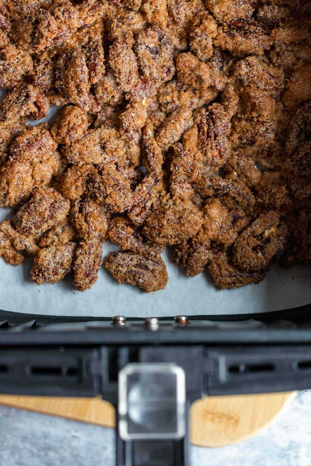 Cooked candied pecans in air fryer basket.