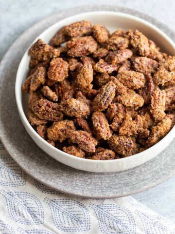 Candied pecans in a white bowl.