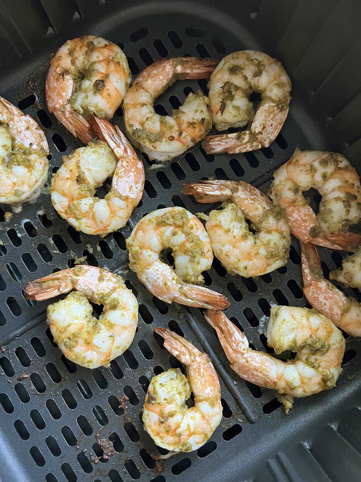 Cooked shrimp in air fryer basket.