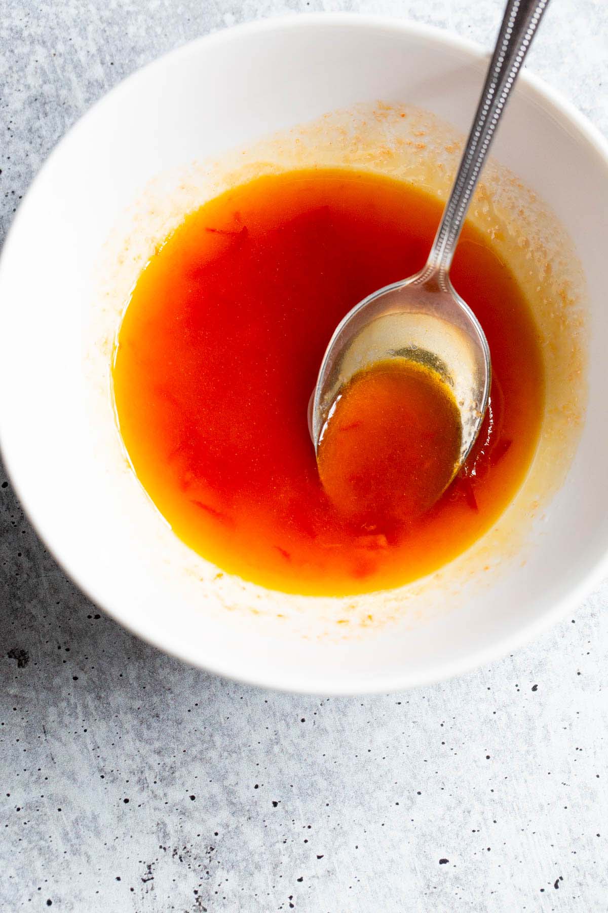 Harissa honey dressing in a bowl with a spoon.