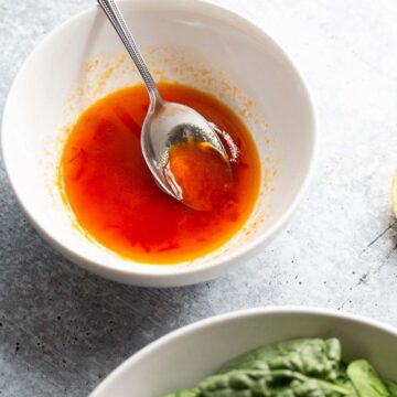 Harissa honey dressing in a bowl with a spoon.