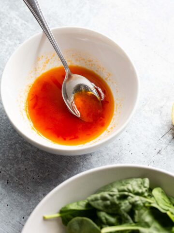 Harissa honey dressing in a bowl with a spoon.