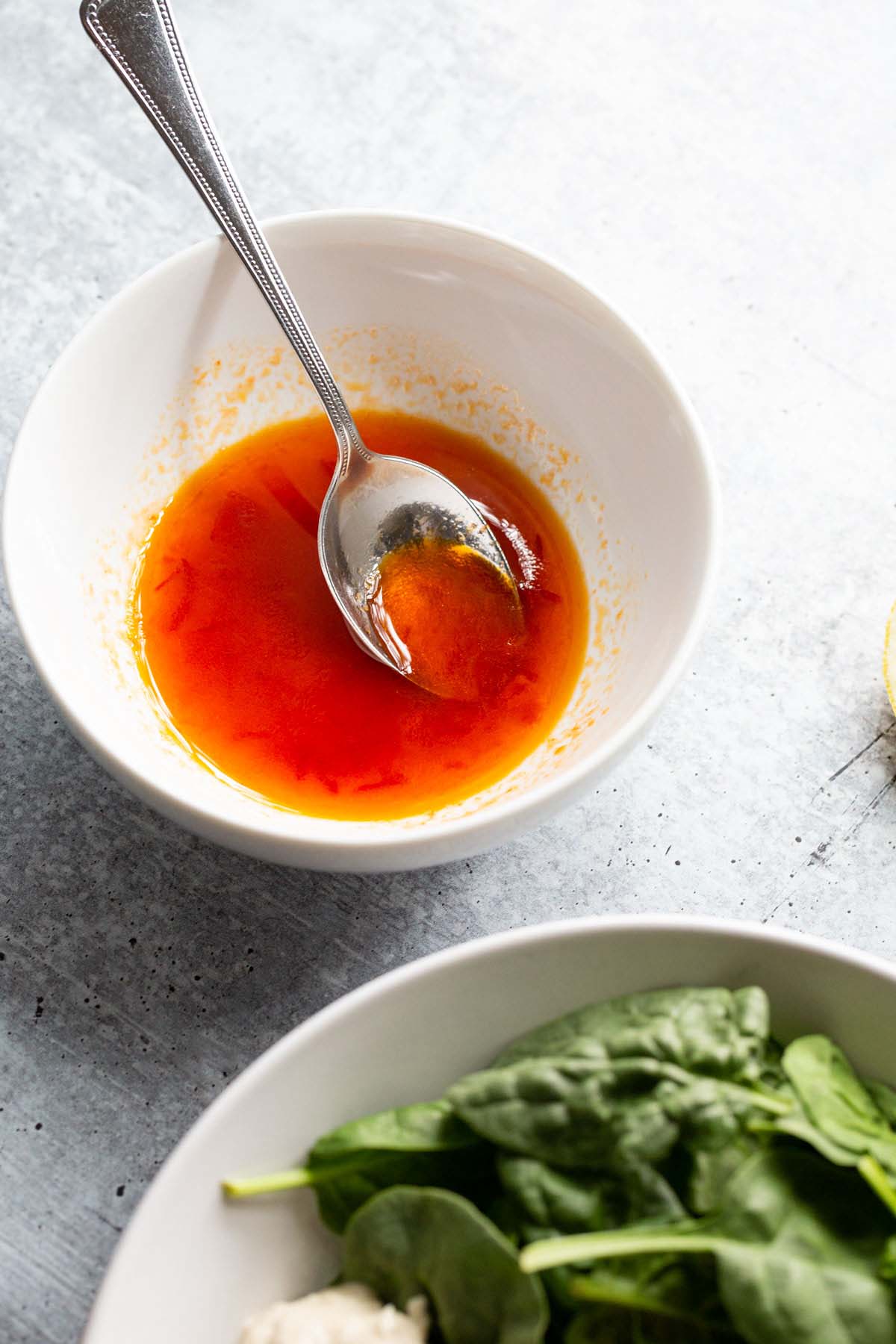 Harissa honey dressing in a bowl with a spoon.