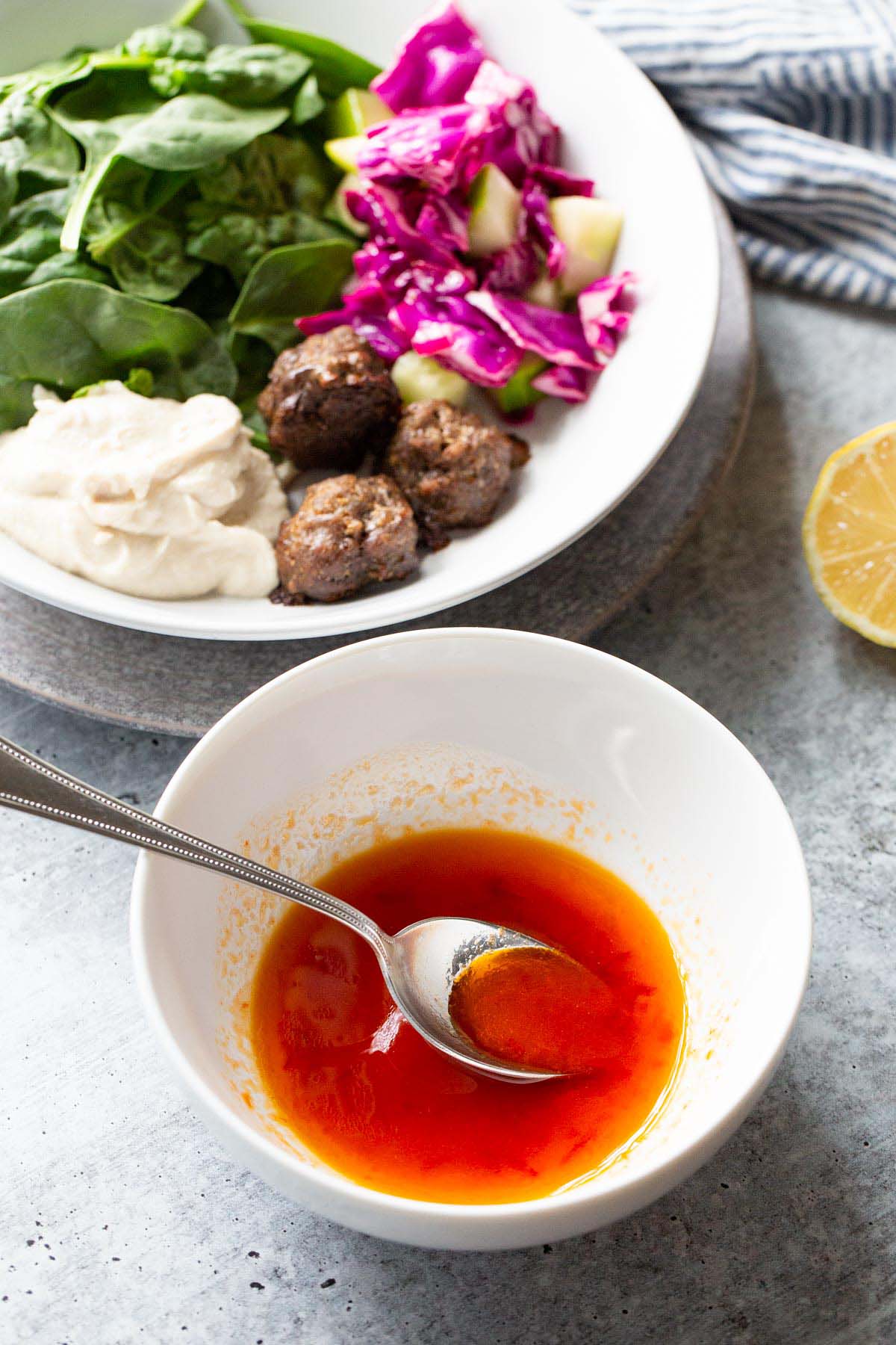 Harissa honey dressing in a bowl with a salad in the background.