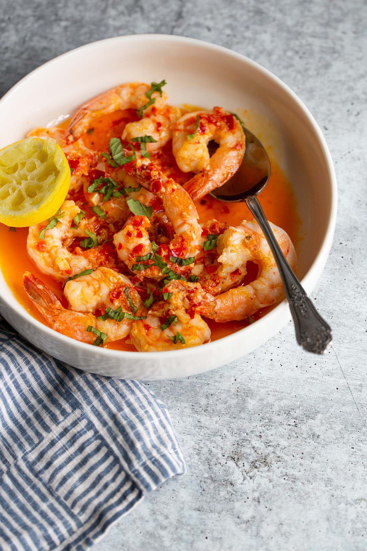 Calabrian shrimp topped with fresh basil in a white bowl.