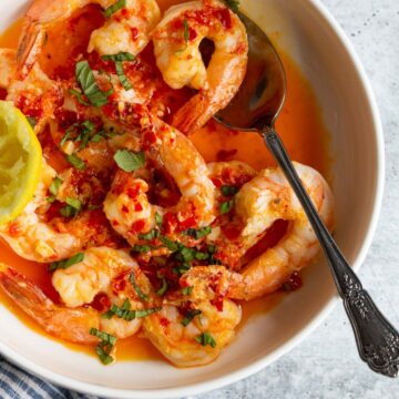 Calabrian shrimp topped with fresh basil in a white bowl.