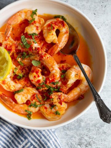 Calabrian shrimp topped with fresh basil in a white bowl.