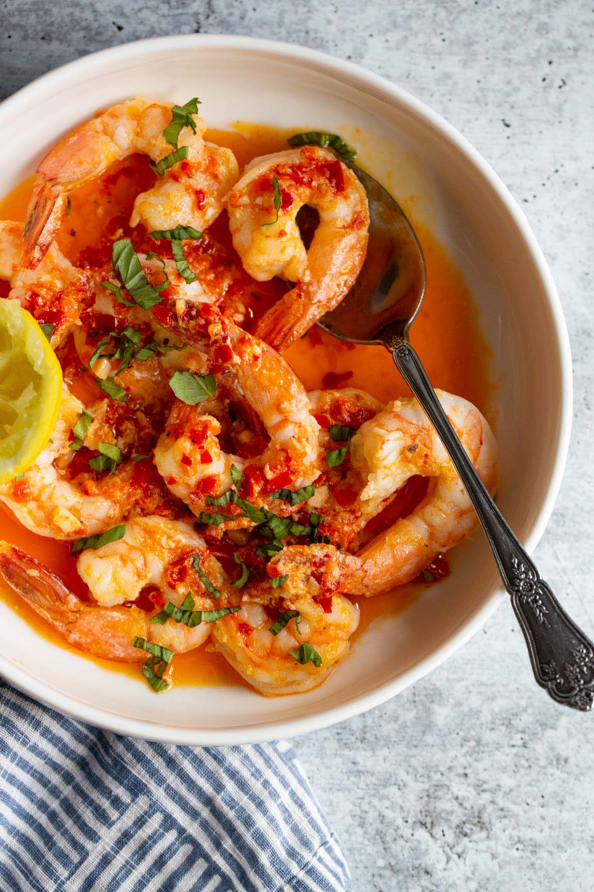 Calabrian shrimp topped with fresh basil in a white bowl.