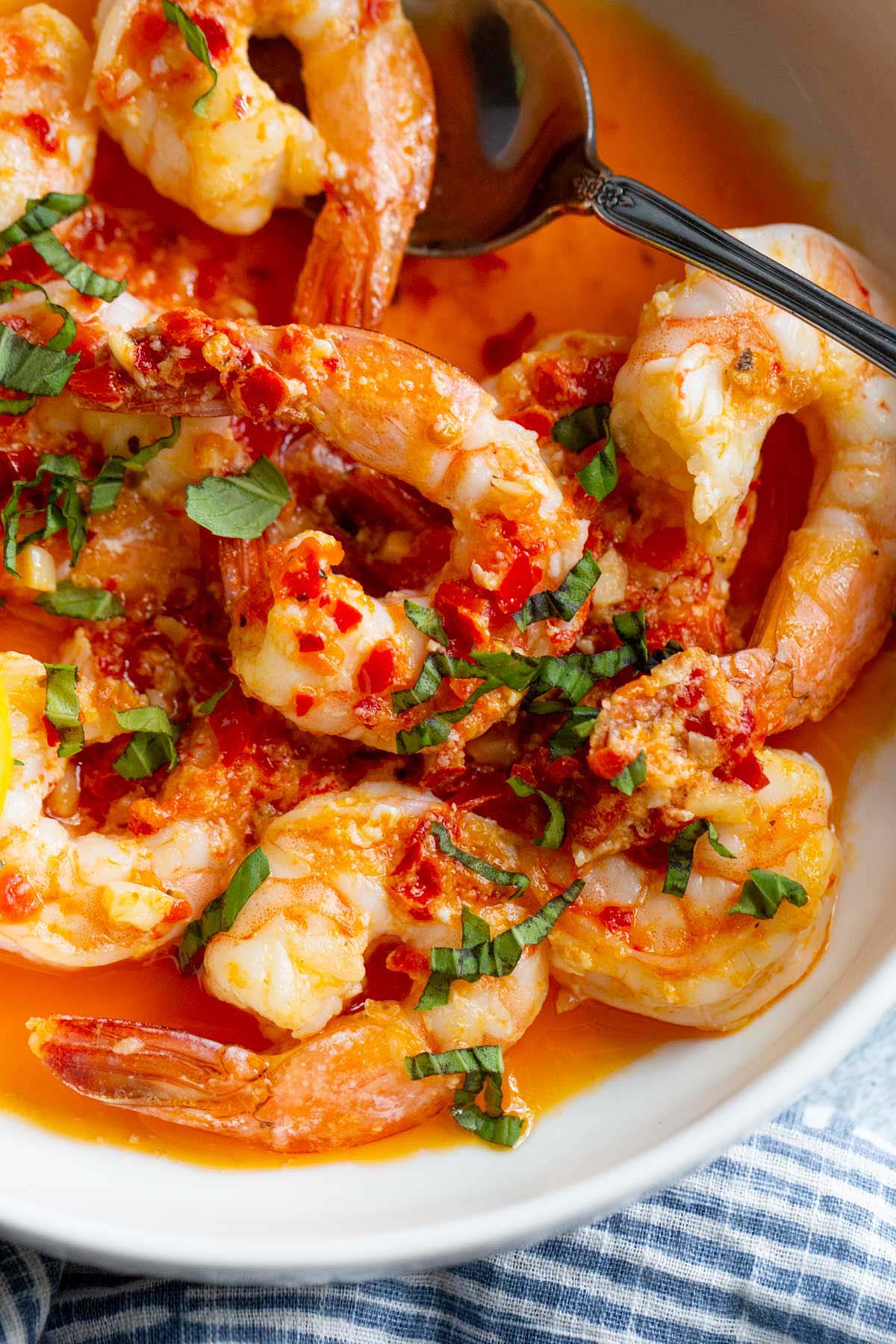 Calabrian shrimp topped with fresh basil in a white bowl.