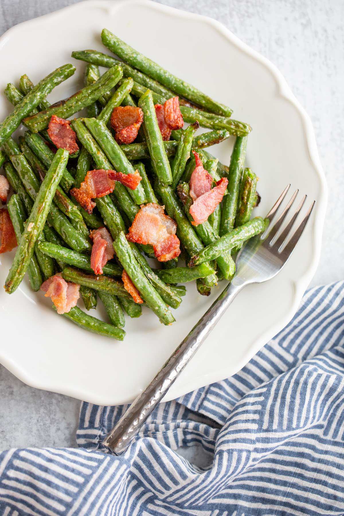 Green beans and bacon on a white plate.